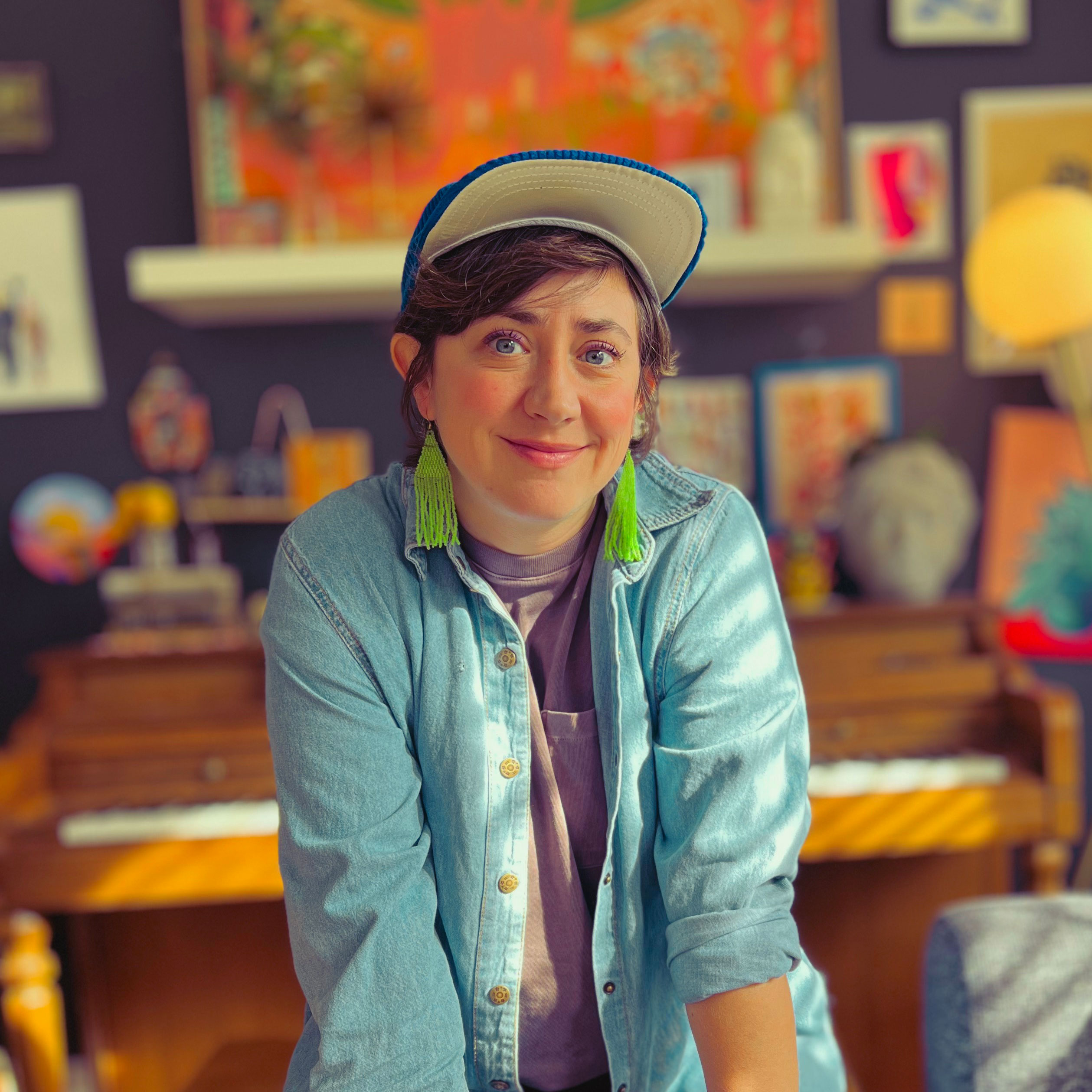 Photo of Karli Fairbanks wearing a hat in front of a piano.